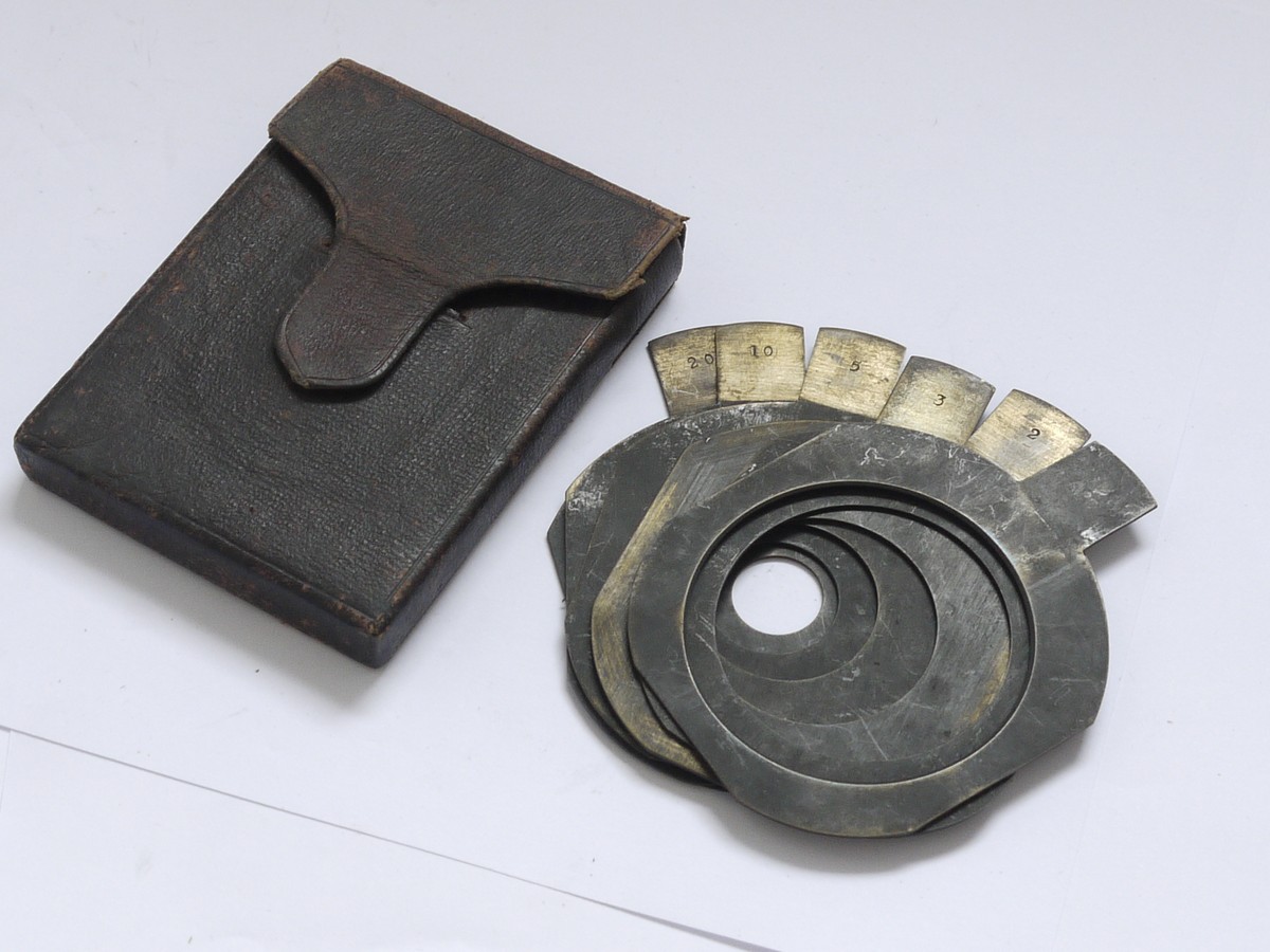 mwclassiccameras-20210604-167 Dallmeyer Waterhouse stops set of Six metal Stops, numbered 1.5, 2, 3, 5, 10 & 20 (72x67mm) with end handle grips, in "Dallmeyer" dark red leather case