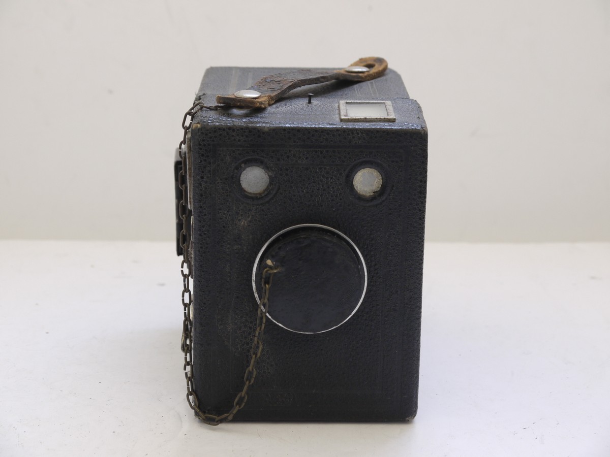 mwclassiccameras-20210716-273 Kodak Six-20 Brownie Junior leatherette covered Box camera, all plain, with added side mounting sports finder & front cap on a chain with metallic Art-Deco patterned front c1934-42. No handle