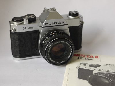 Pentax K1000 35mm SLR, chrome + 50mm f1.7 SMC Pentax-M PK-M mount lens, Skylight filter, front cap & original instructions