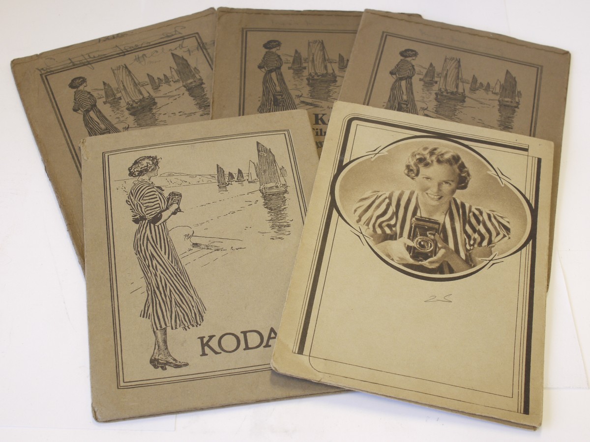 mwclassiccameras-20230526-321 Kodak Film Wallets - set of Five antique paper/card wallets for negatives, four with front images of woman by lake/ocean & one of woman holding eaerly bellows camera