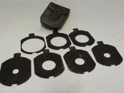 Unamed Waterhouse Stops set of Seven Metal Stops with notch/cut-out at the end. Marked f3.5, f4.8, f5.6, f7, f10, f17 & f13.5 (80x65mm), with end handle grip & Brown leather case. Apparently for use with a Clement & Gilmer Petzval lens c1893