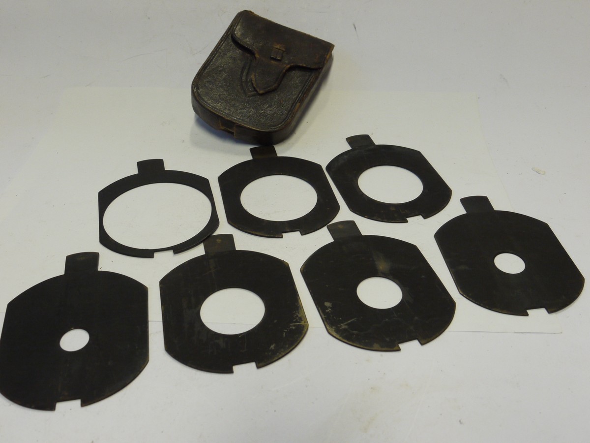 mwclassiccameras-20241129-89 Unamed Waterhouse Stops set of Seven Metal Stops with notch/cut-out at the end. Marked f3.5, f4.8, f5.6, f7, f10, f17 & f13.5 (80x65mm), with end handle grip & Brown leather case. Apparently for use with a Clement & Gilmer Petzval lens c1893