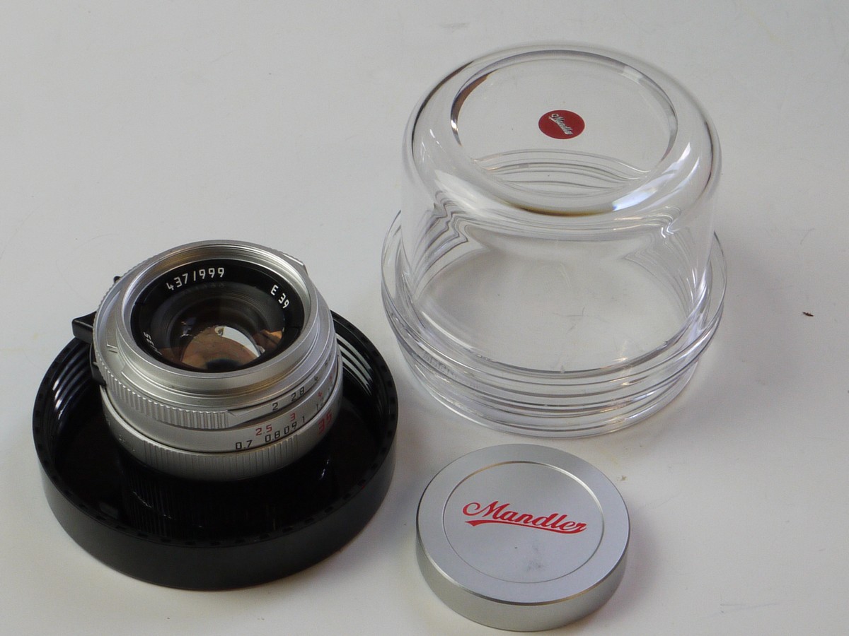 mwclassiccameras-20250606-89 Chinese made Mandler 35mm f2 "Summi-Cron-M" 7-Element Chrome lens based on the Leica 35mm f2 Summicron-M lens. A Well-Regarded, Quality-made lens with very nice bokeh, Made in China in Leica M mount + Mandler E39 UVa filte, Chrome Clip-on lens hood with vents, Black Clip-on Square shaped lens hood, Mandler front cap, Hood/filter Boxes, keeper case, Main Box with packaging & Outer Box.