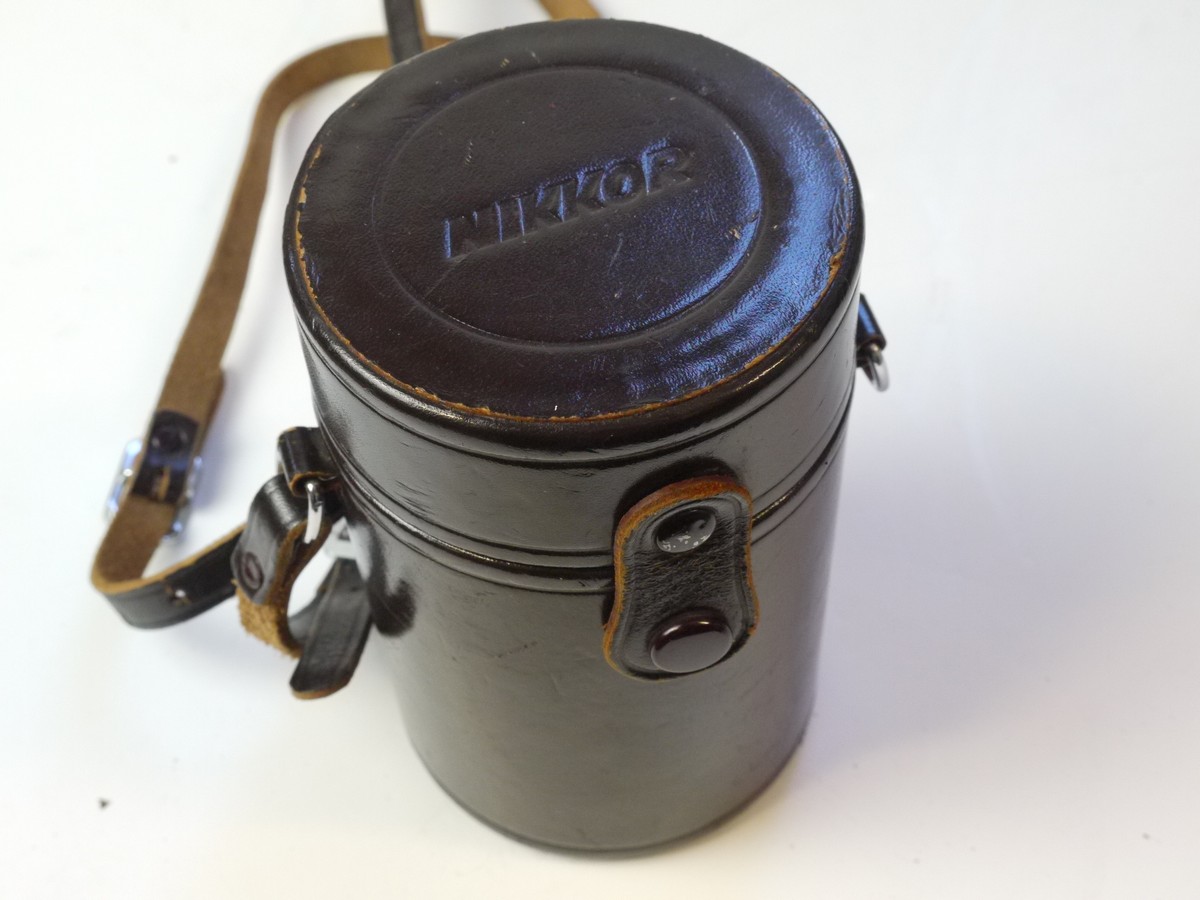 mwclassiccameras-20250829-210 Nikon brown leather lens case, marked "Nikkor" on top, with strap & with red felt inlay. 138 x 83mm